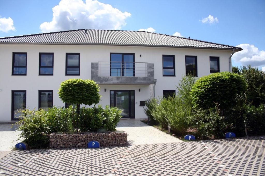 a white building with bushes in front of it at Hotel HeideZeiten in Walsrode