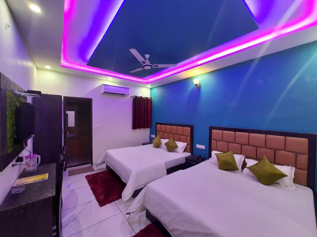 a room with two beds and a ceiling with purple lights at AK Residency in Haridwār