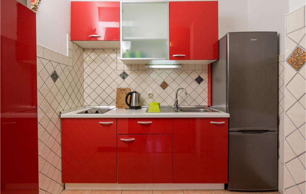 kuchnia z czerwonymi szafkami i lodówką w obiekcie Lovely Apartment In Stara Novalja w mieście Stara Novalja
