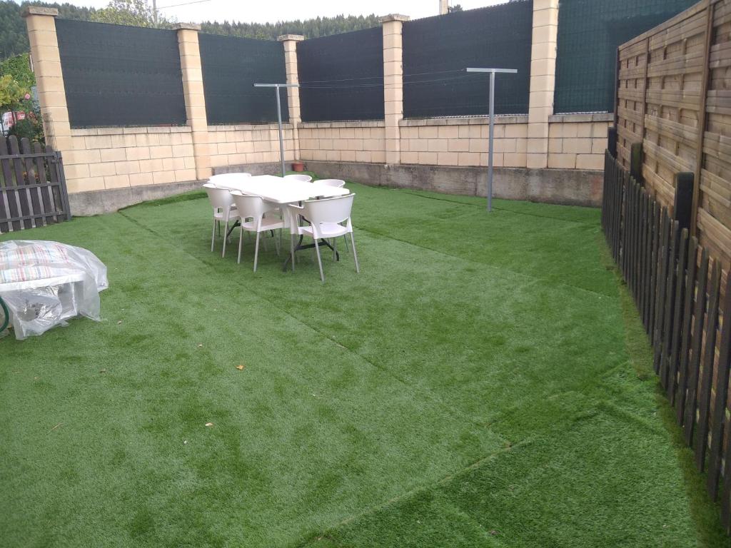 un patio con mesa y sillas sobre hierba en Casa Bayona, en Monte