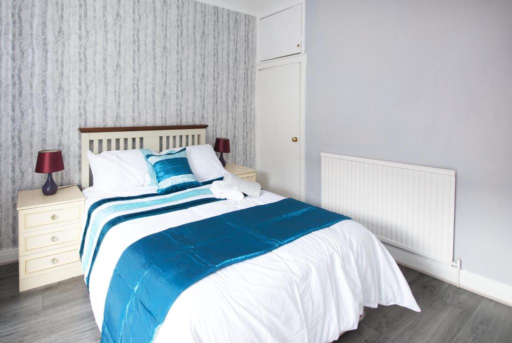 a bedroom with a large bed with blue and white sheets at Crystal House 10min to Manchester City Centre ideal for work and leisure in Manchester