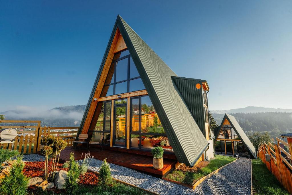 a small house with a triangular roof with glass windows at Krest relaxing heights in Vatra Dornei