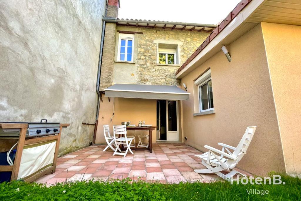 a patio with a table and chairs in front of a house at CLIM Jolie maison de 60 m2 avec jardin in Limoges