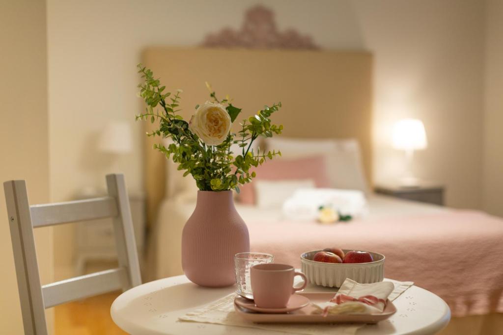 een tafel met een vaas met bloemen en een fruitschaal bij Casa dos Troviscais in Lousã