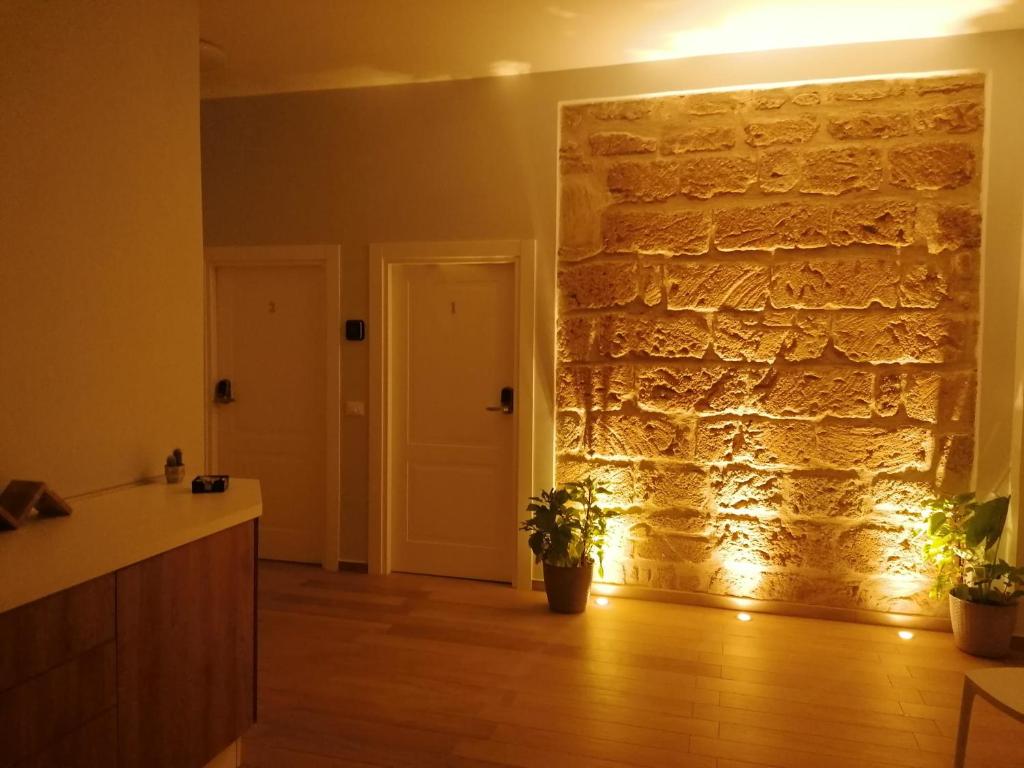 una cocina con una pared de piedra con luces en Nike Luxury Rooms en Agrigento