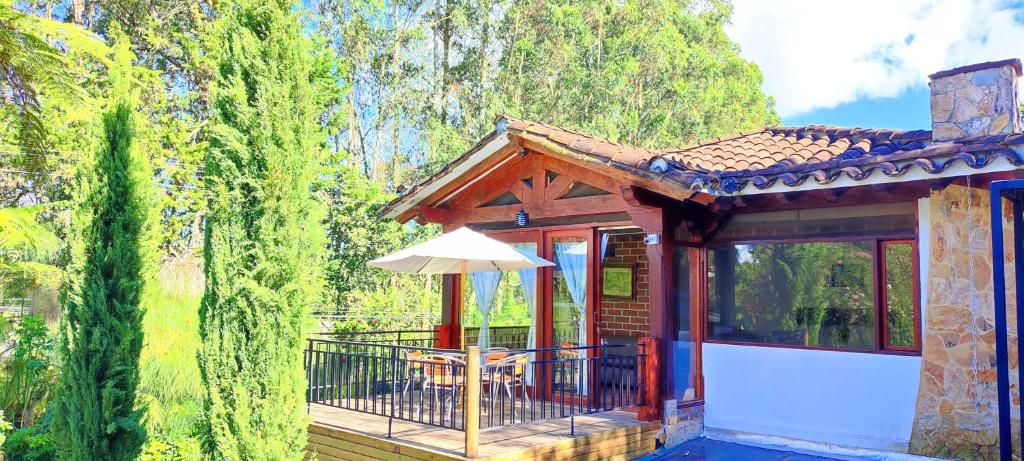 a house with a deck with a table and an umbrella at La Martina Campestre in Rionegro