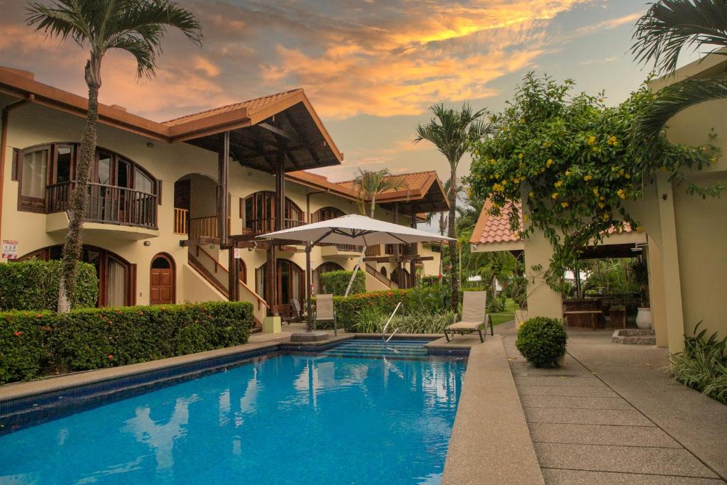 uma villa com piscina em frente a uma casa em Apartotel Girasol em Jacó