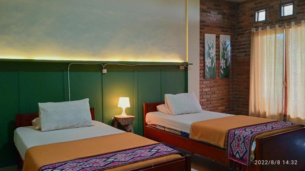 Cette chambre comprend deux lits et une lampe sur une table. dans l'établissement Ecobromo, à Pasuruan