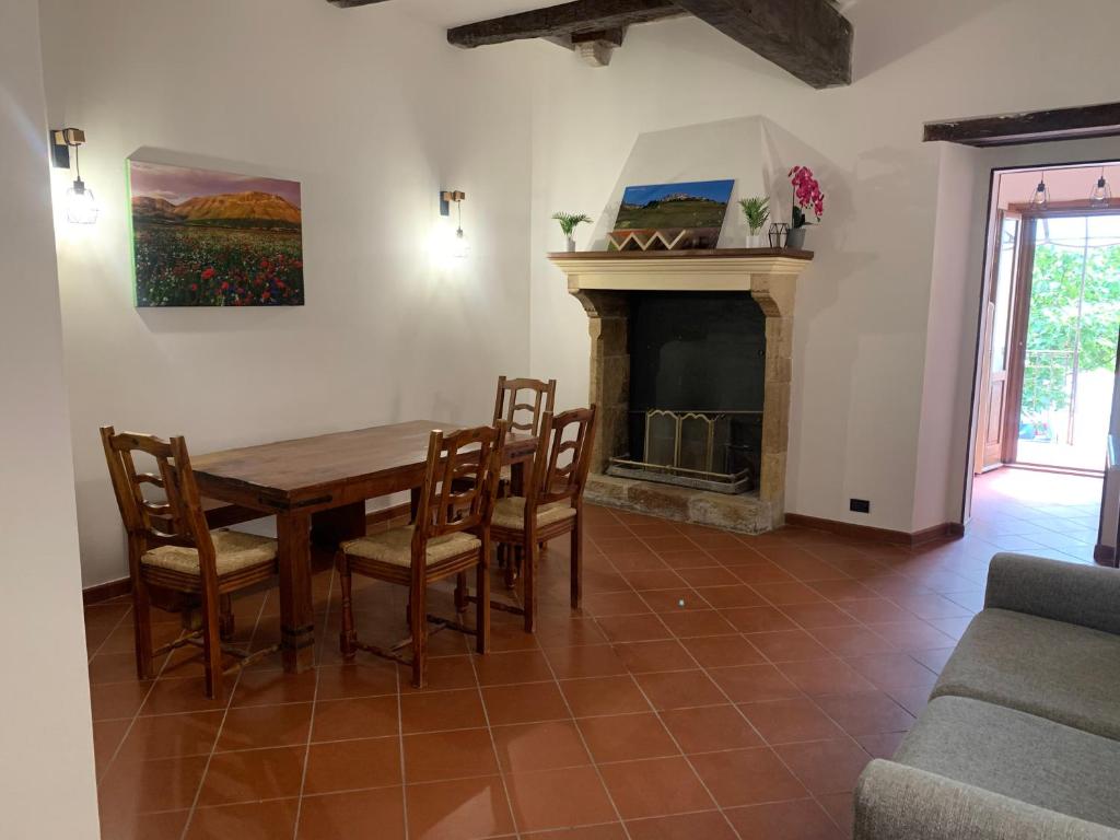 una sala da pranzo con tavolo, sedie e camino di Residence il giardino sul fiume Nera a Cerreto di Spoleto