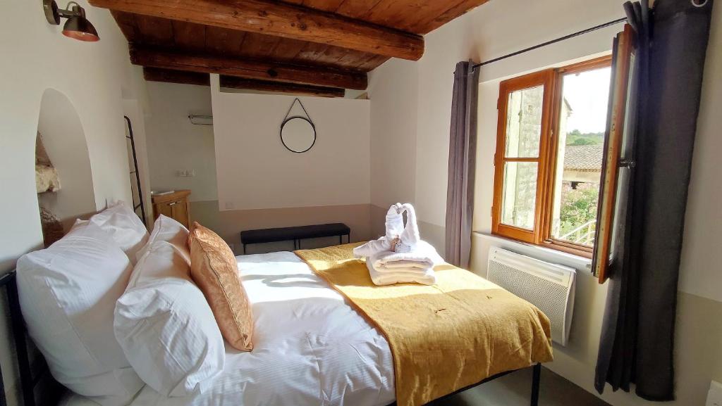 una camera da letto con un letto con lenzuola bianche e una finestra di PROCHE UZES LE COCON DU PEINTRE ANGLAIS a Sanilhac-et-Sagriès