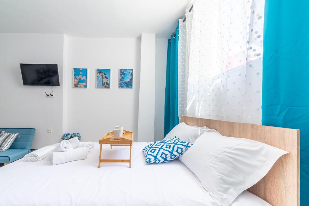 a bedroom with a bed with white sheets and blue curtains at Brand New Studio near Downtown in Heraklio