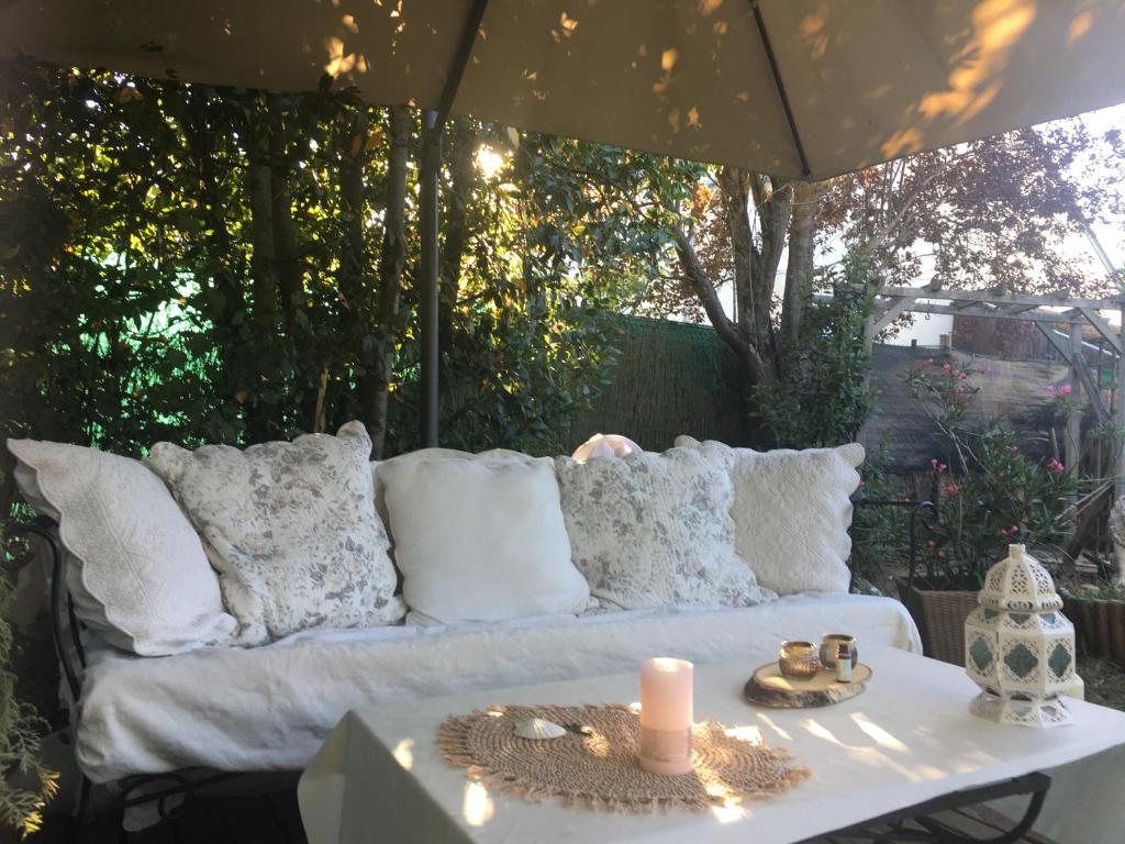 a white couch with pillows and a candle on a table at Le Havre de paix in Saint-Cyr-sur-Loire