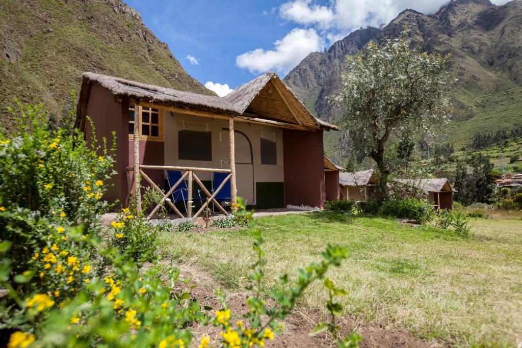 ein Haus auf einem Feld mit Bergen im Hintergrund in der Unterkunft Inca Trail Glamping in Cusco