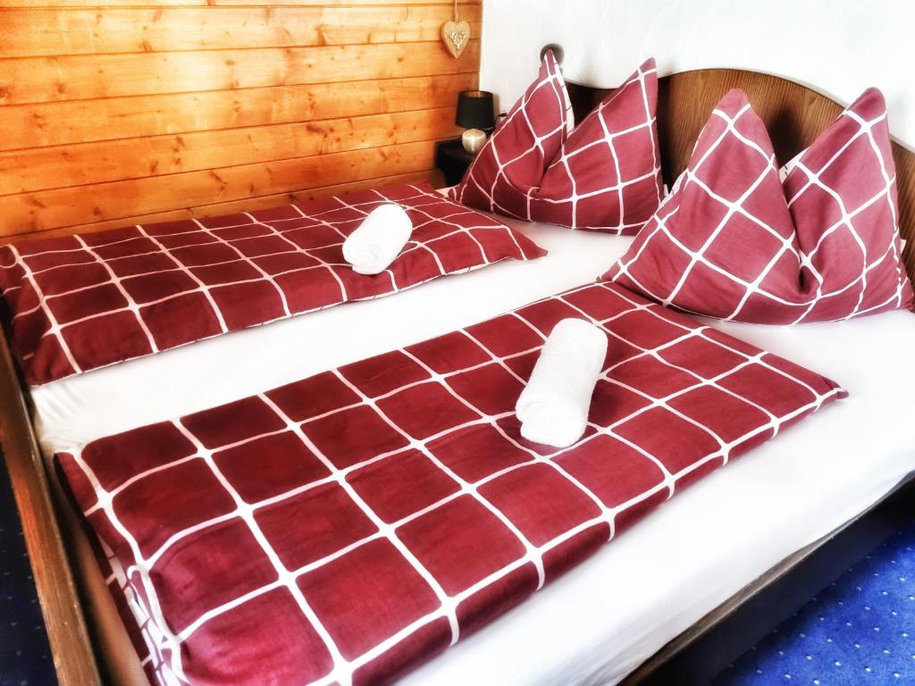 Cama con sábanas y almohadas rojas y blancas en das Bergerleben, en Sonnenalpe Nassfeld
