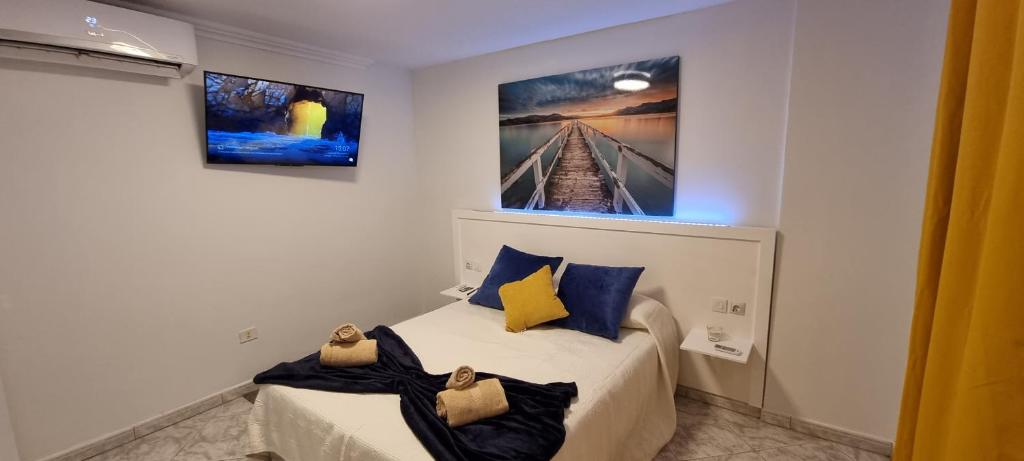a bedroom with a bed with blue and yellow pillows at SUMMERLAND SUNSET in Los Cristianos