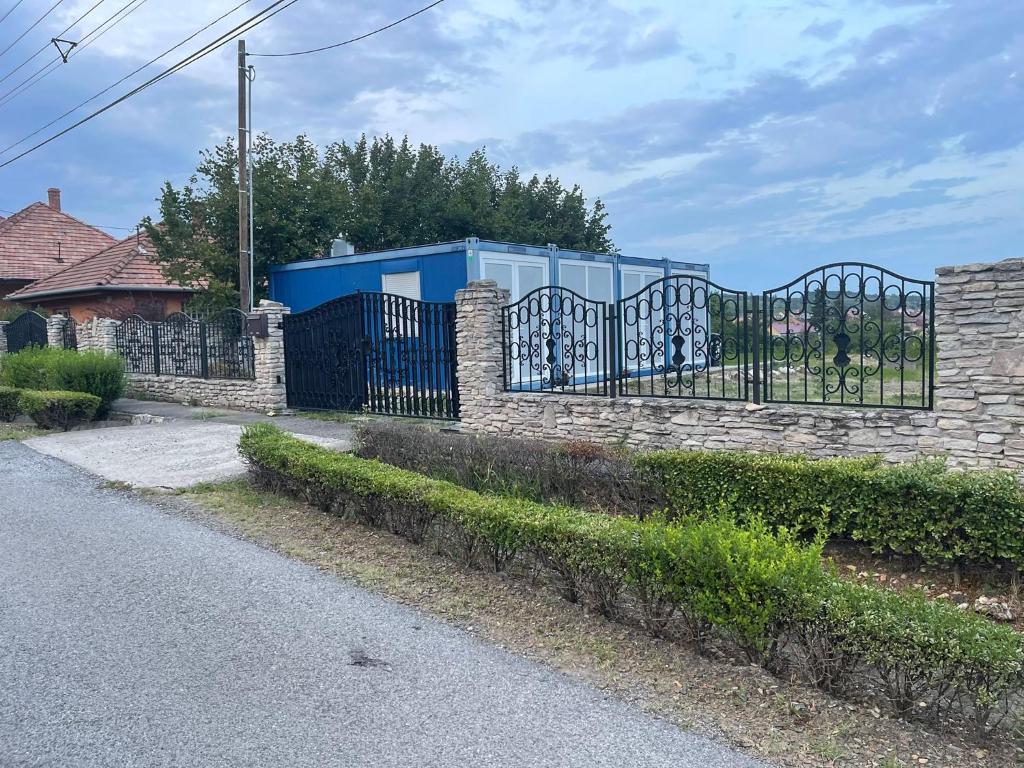 a gate in a stone fence in front of a house at LakePark Apartman in Bekecs