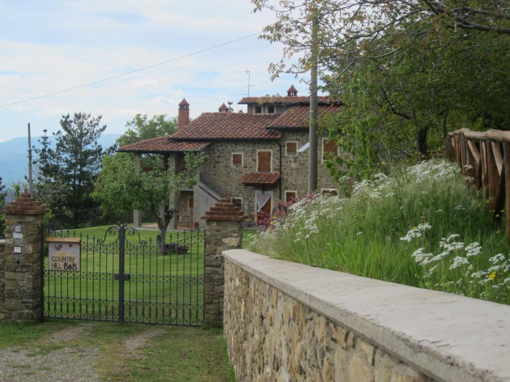 una casa con una valla de piedra y una puerta en Bed and Breakfast Country Hill, en Arezzo