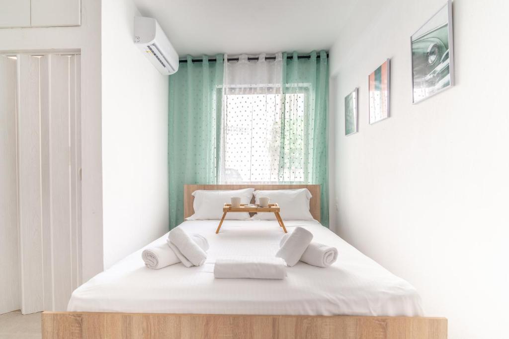 a white bedroom with a bed with white pillows at Renovated Studio near Downtown in Heraklio