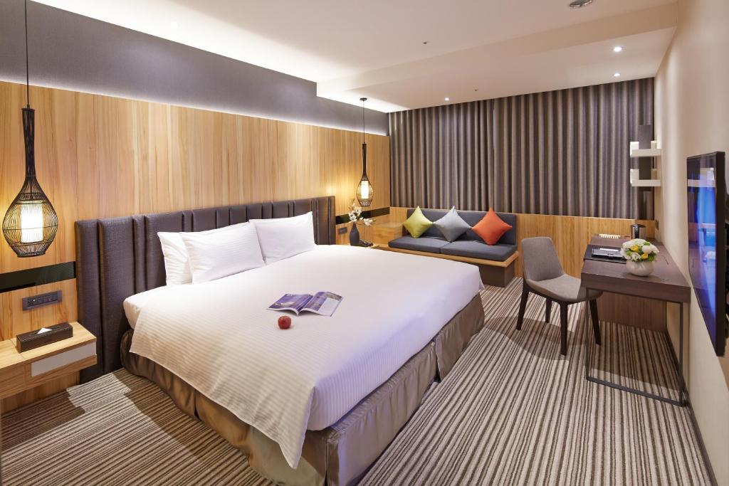 a hotel room with a large bed and a desk at La Vida Hotel in Taichung