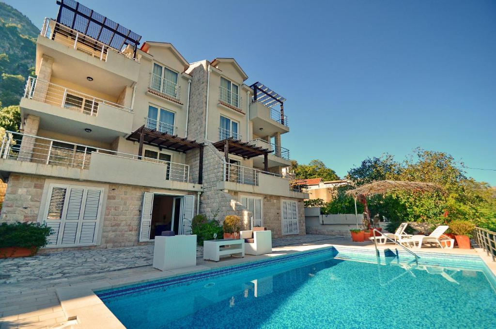 a villa with a swimming pool in front of a building at Muo Apartments in Kotor