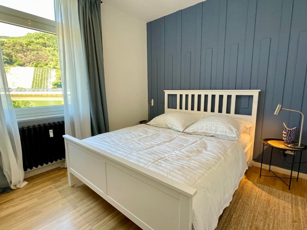 um quarto com uma cama branca e uma parede azul em RiversideSuite.Mosel em Neumagen-Dhron