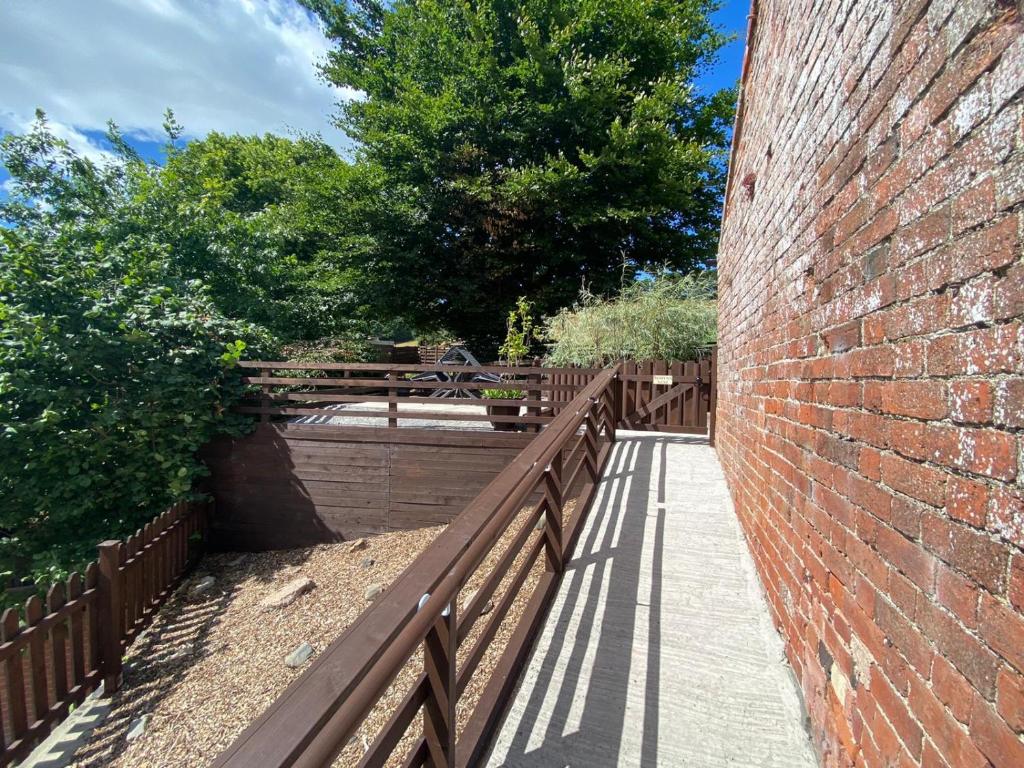 a brick wall with a wooden fence next to a sidewalk at Robyns Nest, self catering cottage in Welshpool