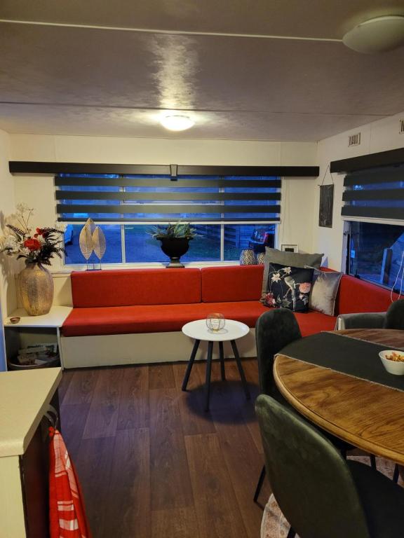 un soggiorno con divano rosso e tavolo di Eexter bosparel caravan 222 a Eext