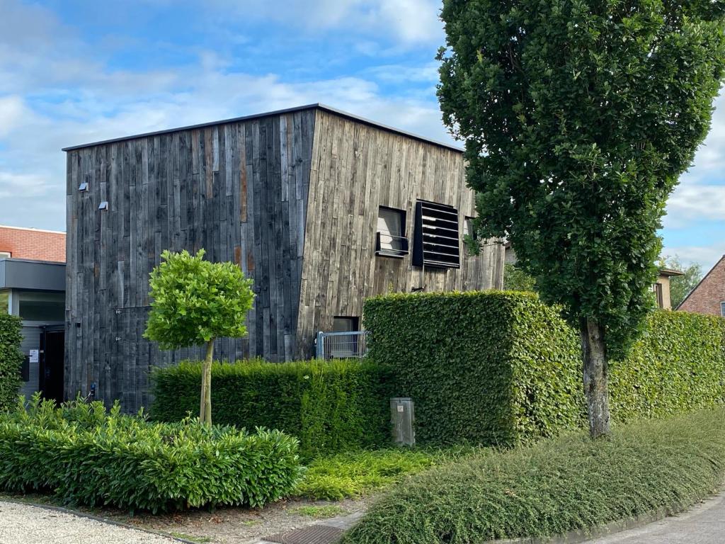 un edificio de madera con una ventana y un árbol en atelier2, en Hamont