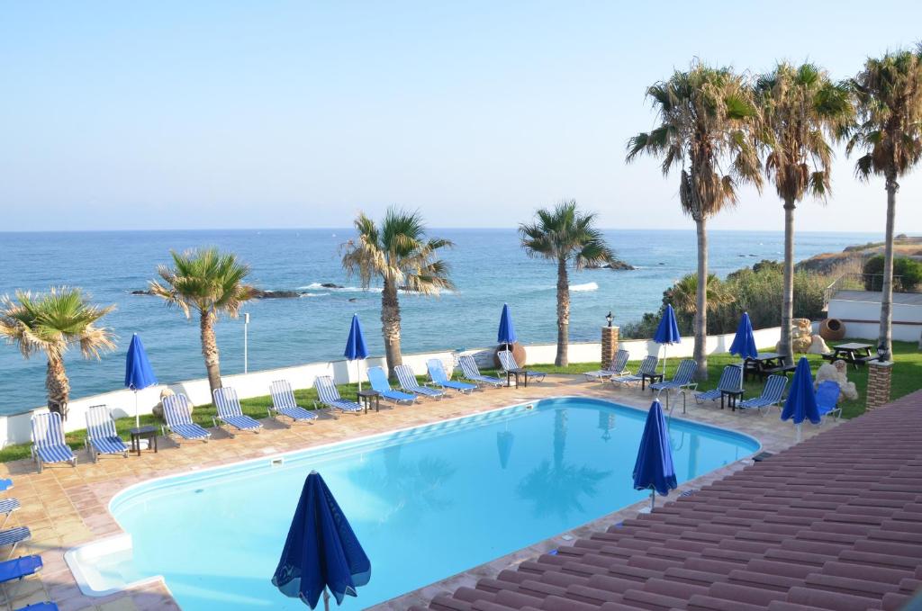 una piscina con sillas, palmeras y el océano en Sun Camero Apartments, en Pomos