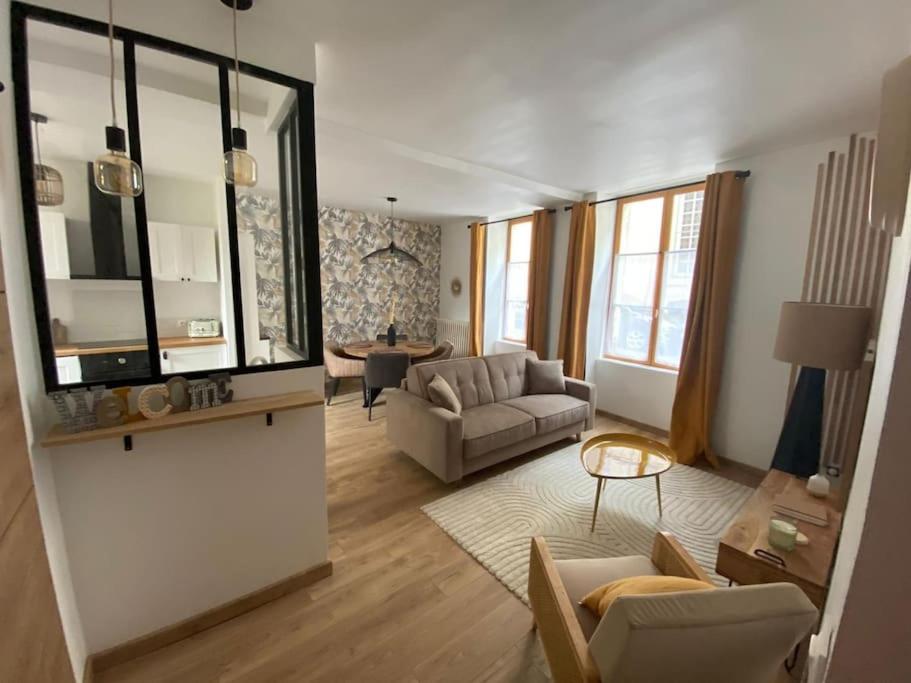 ein Wohnzimmer mit einem Sofa und einem Tisch in der Unterkunft L'Ilot du Perche: Appartement cosy avec jardin in Bellême