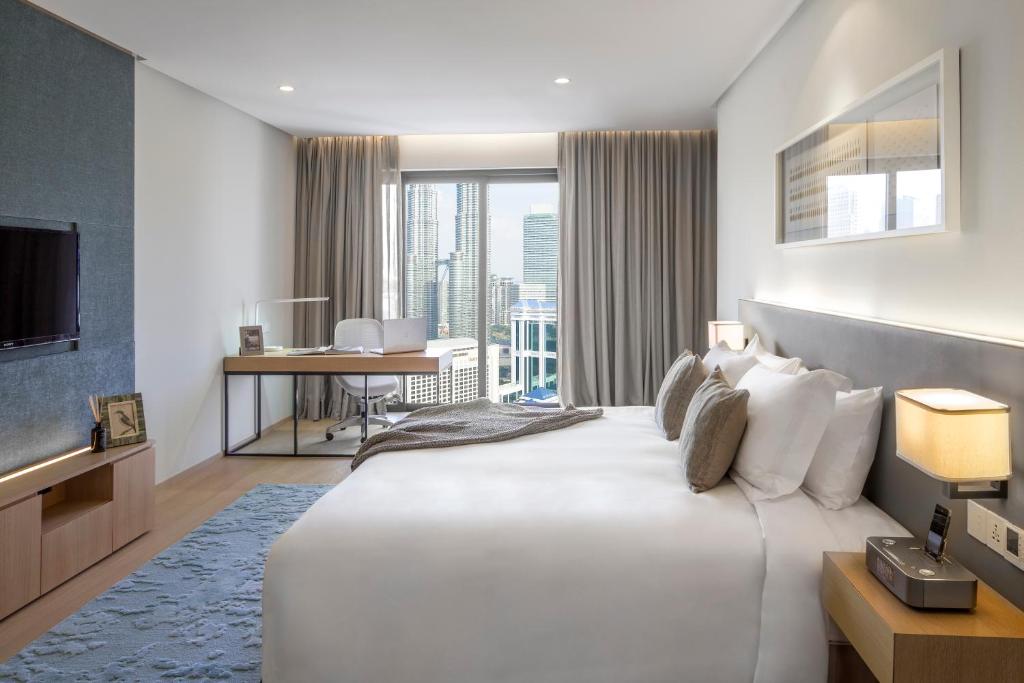 Habitación de hotel con cama blanca grande y escritorio. en Sfera Residence Kuala Lumpur City Centre, en Kuala Lumpur