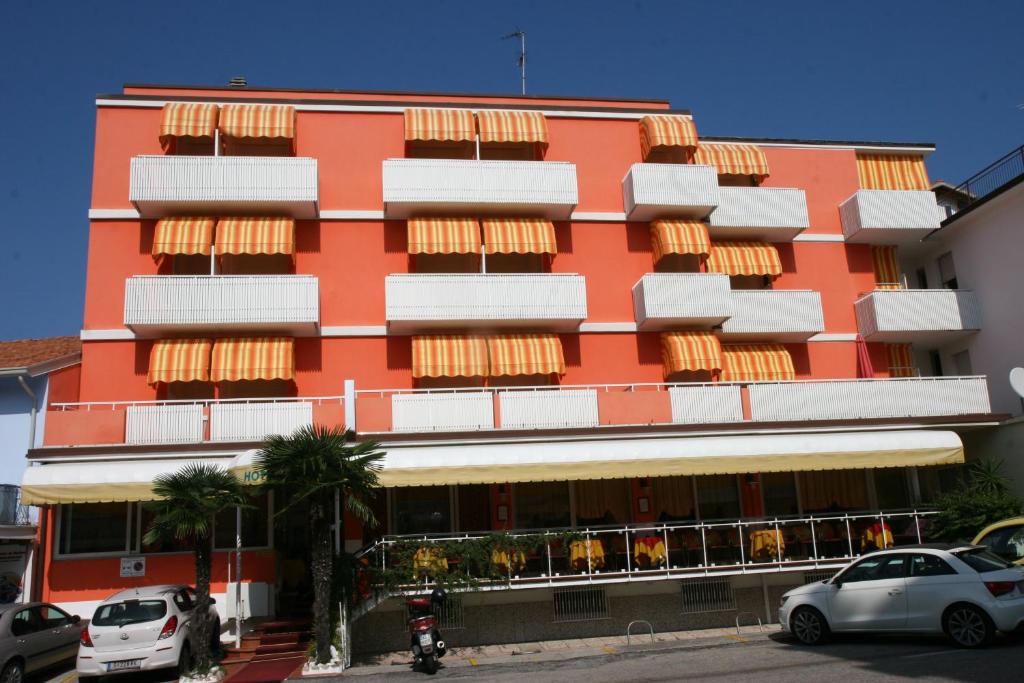 un alto edificio arancione con macchine parcheggiate di fronte di Hotel Paron a Bibione