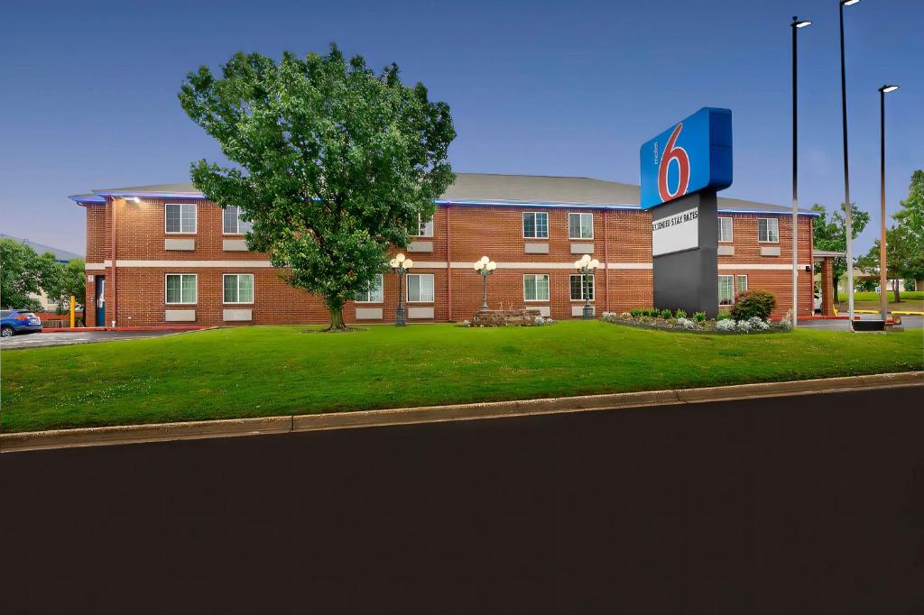 un gran edificio de ladrillo con un árbol delante de él en Motel 6 Tulsa, Ok - Central, en Tulsa