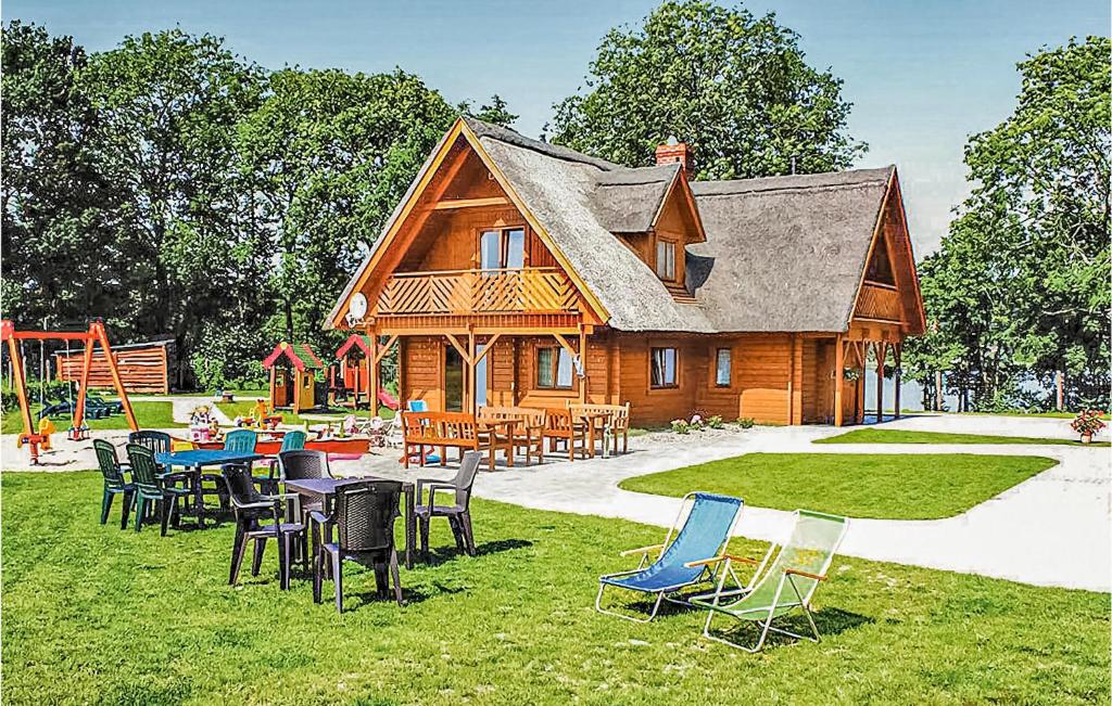 una casa in legno con sedie, tavoli e un parco giochi di Zakatek Mala a Kołczewo