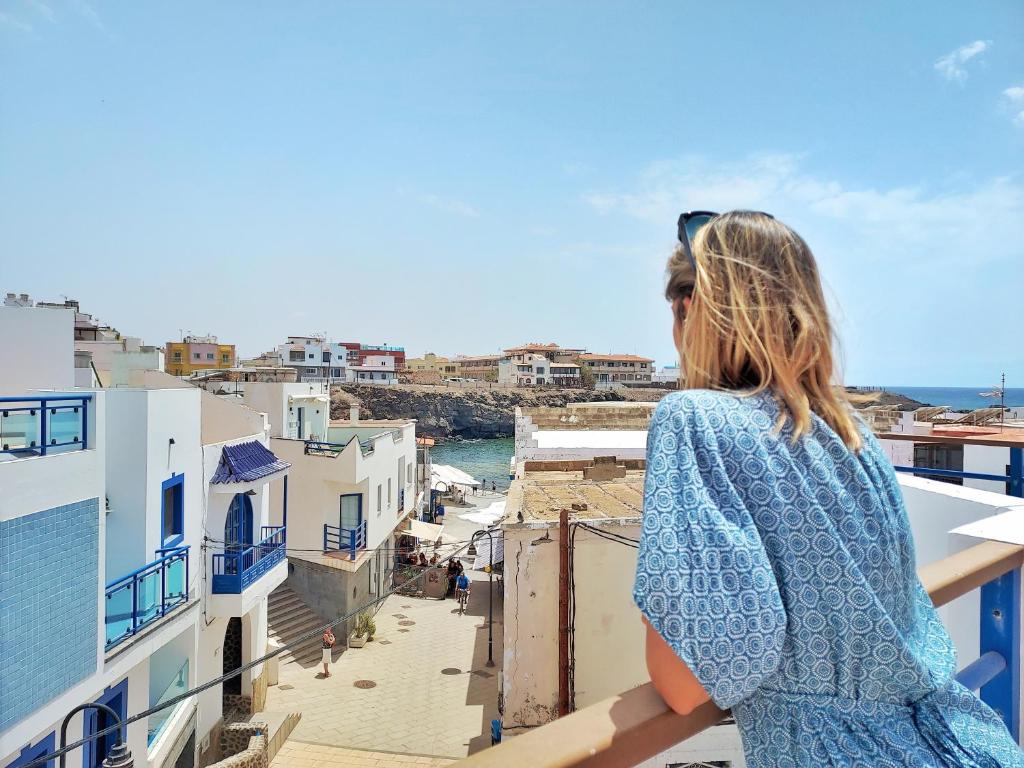 a woman standing on a balcony looking out at the ocean at Cotillo Ocean in El Cotillo