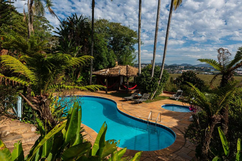 a swimming pool with a gazebo and palm trees at Pousada Recanto das Rosas in Bragança Paulista