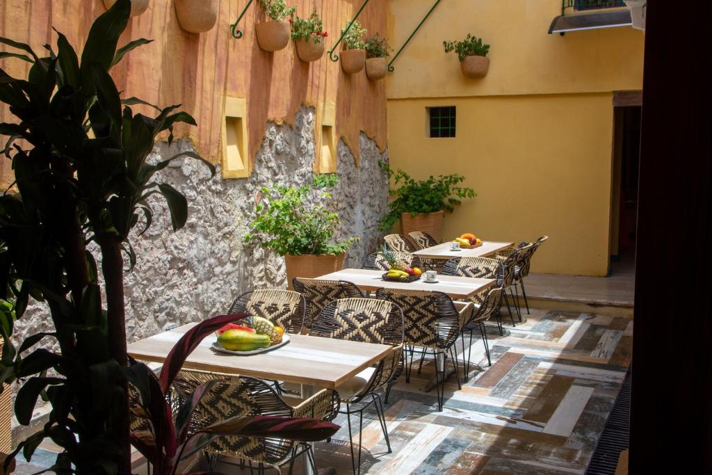 a patio with tables and chairs and a stone wall at Casa Lorenza Hotel in Cartagena de Indias