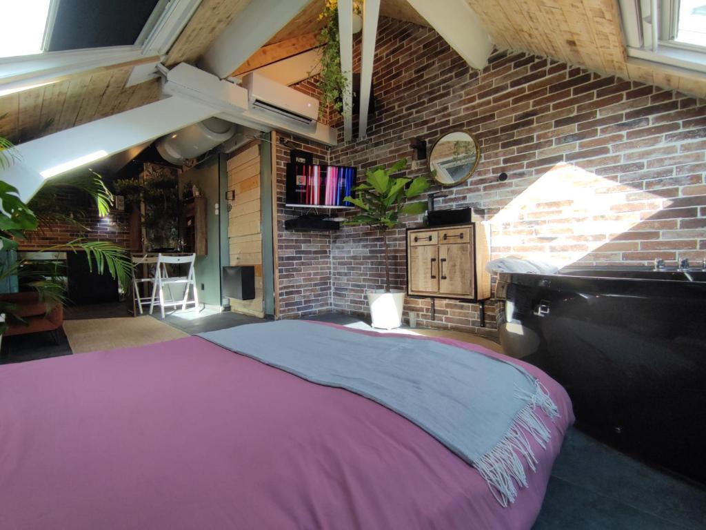 a bedroom with a large bed in a brick wall at La cachette sous les toits balnéo climatisé in Nantes