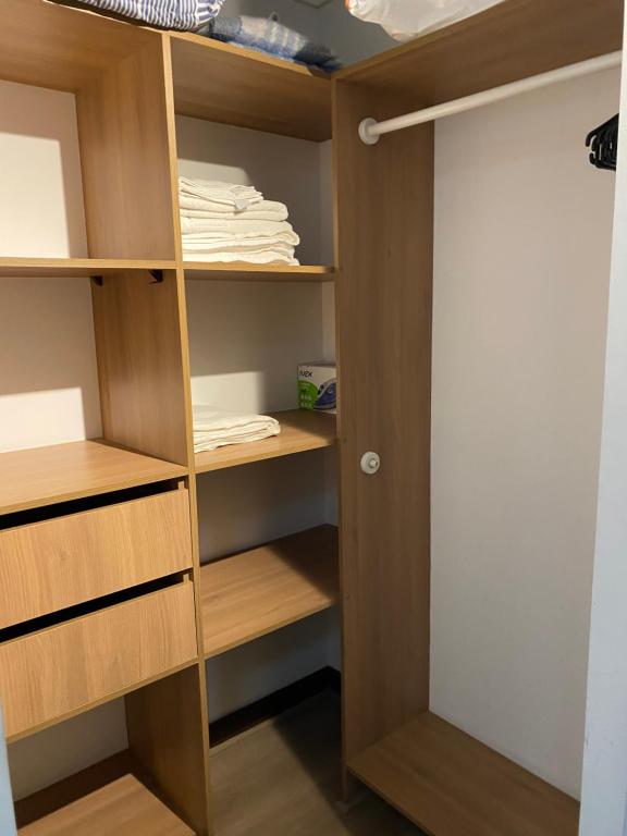 Armario con estanterías de madera y toallas blancas en Departamento a pasos de Clinica Las Condes- Estoril en Santiago