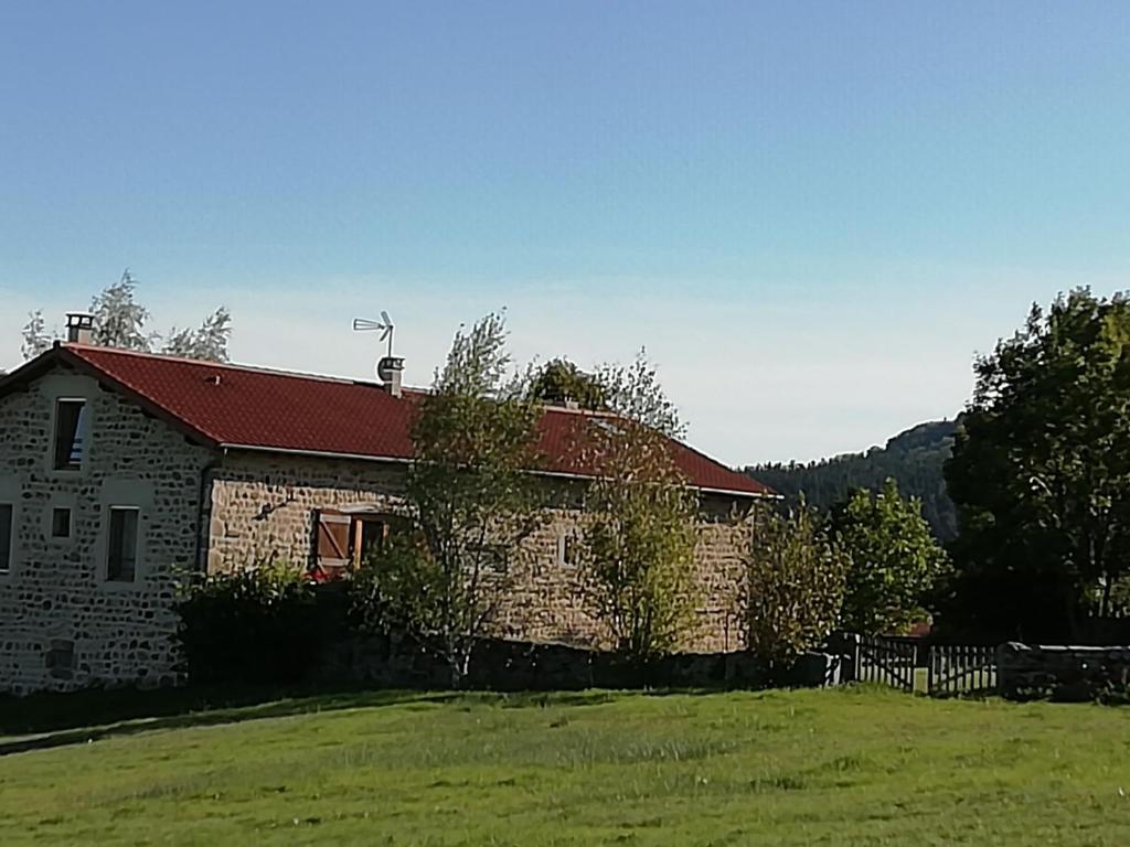 a brick house with a red roof in a field at Gîte familial avec équipement bébé, terrasse et jardin clos à Roche-en-Régnier - FR-1-582-192 in Roche-en-Régnier