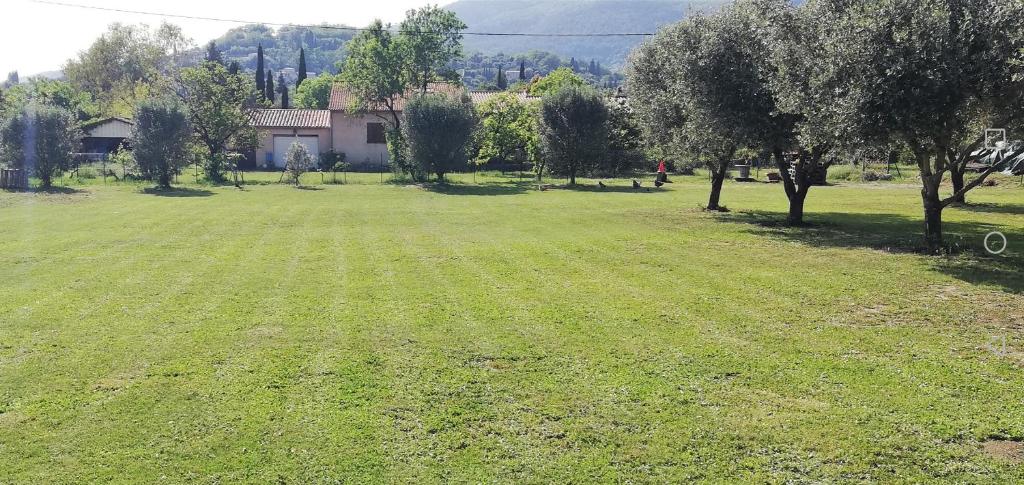 un grand champ verdoyant avec des arbres et une maison dans l'établissement Villa Graziella, à Châteauneuf