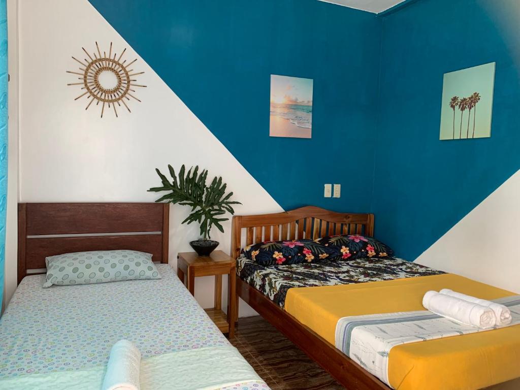 2 łóżka w pokoju z niebieskimi ścianami w obiekcie Pisces Tourist Inn - Port Barton w mieście San Vicente