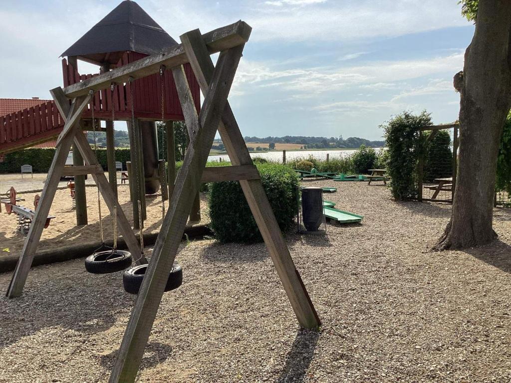 a wooden playground with a swing set and a tree at 4 person holiday home in Hejls-By Traum in Hejls