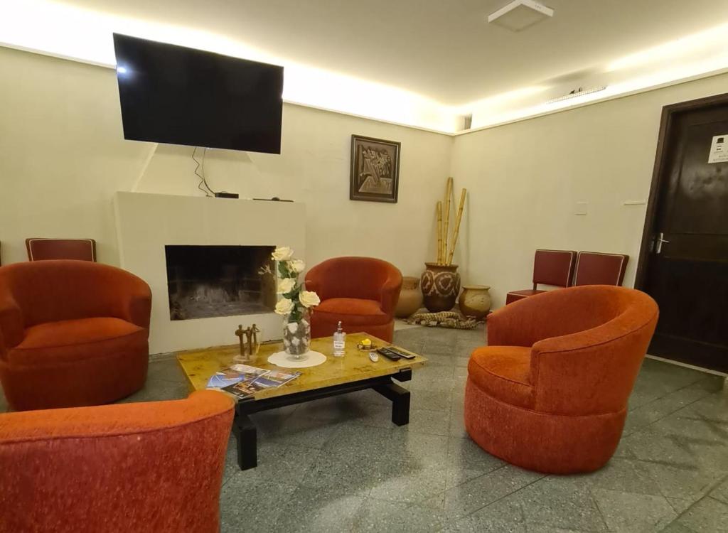 un soggiorno con sedie arancioni, tavolo e TV di Hotel Hassler ad Asunción