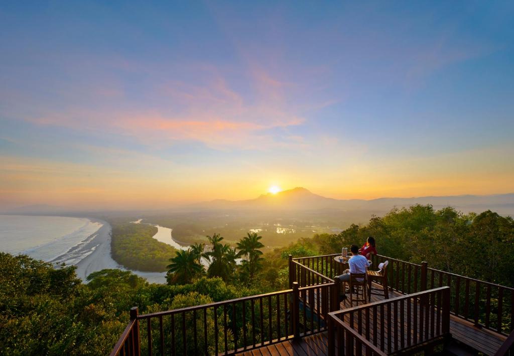 un grupo de personas sentadas en una terraza con vistas a la puesta de sol en Shangri-La Rasa Ria, Kota Kinabalu en Kota Kinabalu