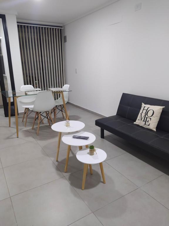 ein Wohnzimmer mit einem schwarzen Sofa und Tischen in der Unterkunft Brasil flats-Nueva Cordoba in Cordoba