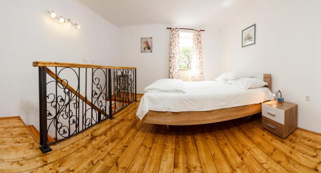 a bedroom with a bed and a wooden floor at Apartment Kalajžić Žeževica in Žeževica