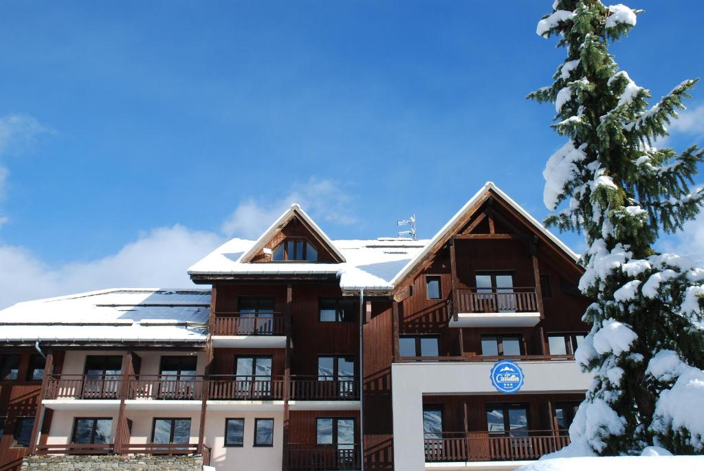 duży budynek apartamentowy ze śniegiem na dachu w obiekcie Hôtel Club "Les Carrettes" w mieście Valmeinier