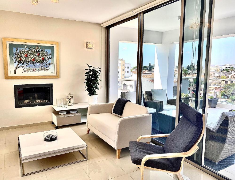 ein Wohnzimmer mit einem Sofa, Stühlen und einem Kamin in der Unterkunft The Penthouse 401 in Larnaka