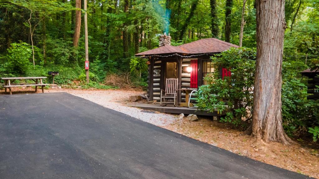 a small cabin in the woods with a bench at Log Cabin Motor Court in Asheville